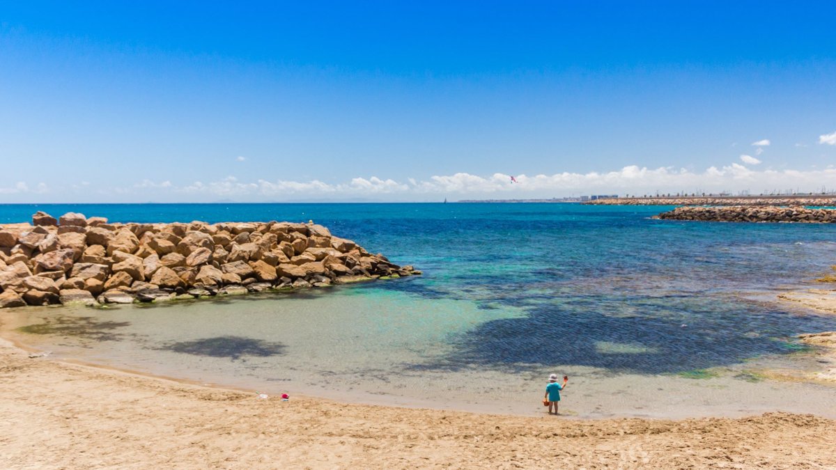 Child playing by the shoreline on a calm beach in Torrevieja